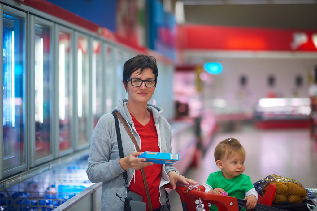 Mum with young child reading food labels in a supermarket